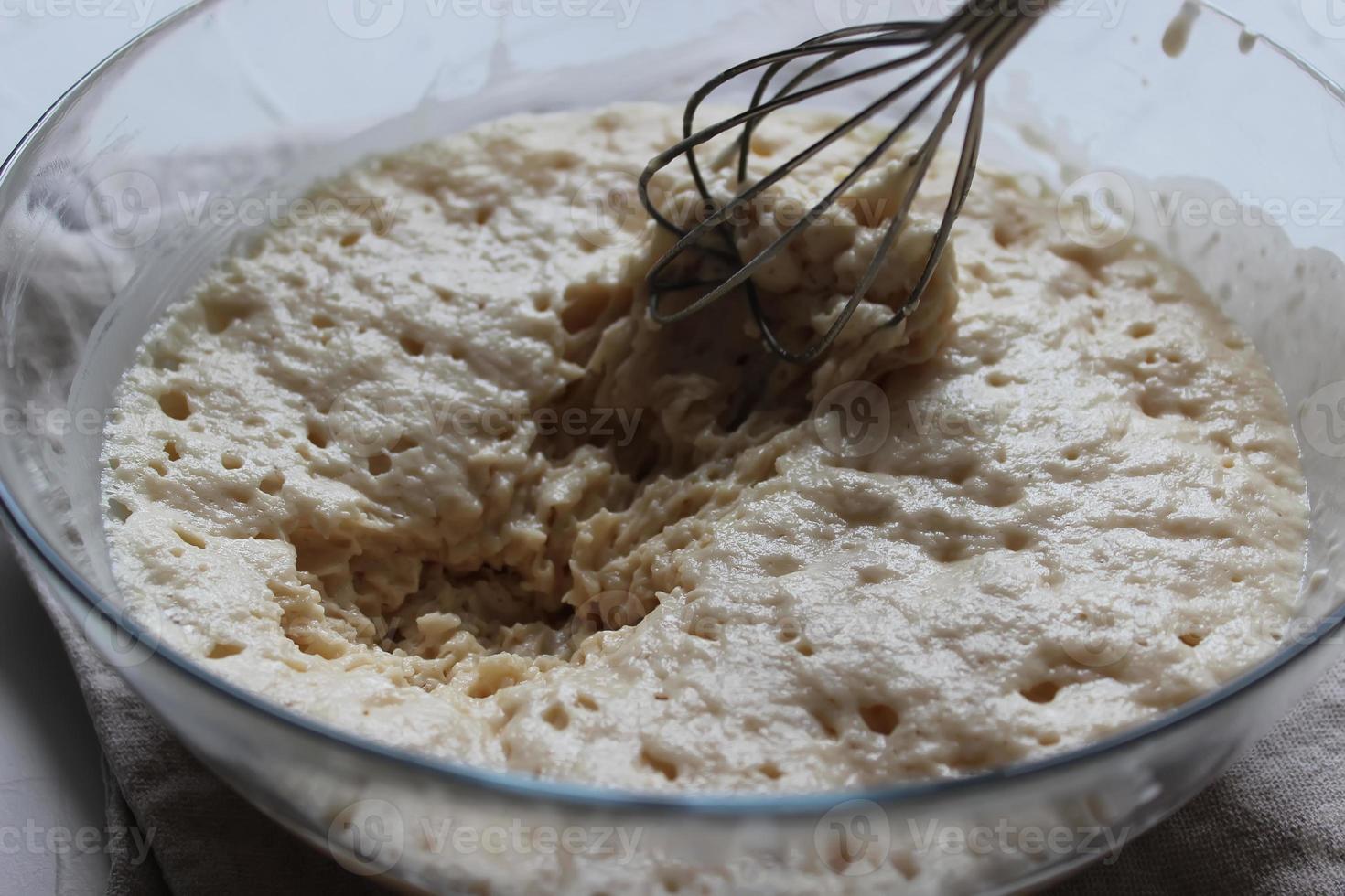 Batter with a whisk in a large glass bowl. Homemade cake. Concept of homework during the quarantine period. photo
