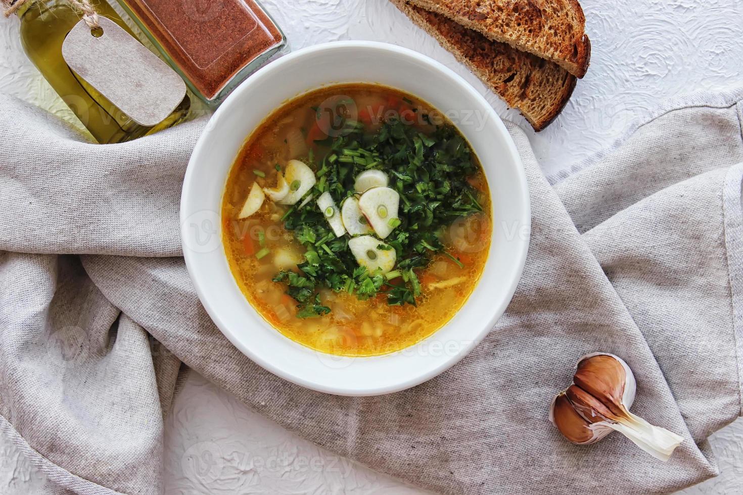 Lentil soup with garlic and herbs in a white bowl on the table. Diet, home-cooked food. photo