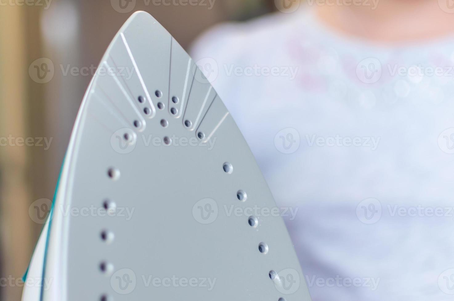 iron in the hand of the girl on the Ironing Board irons and steams clothes photo