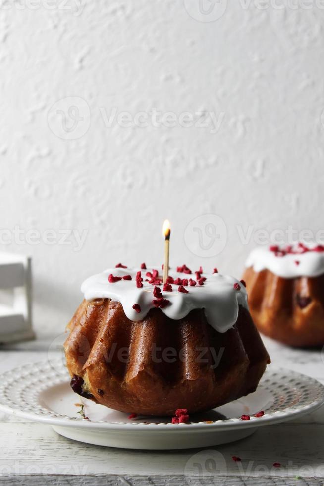 Rum baba poured with white icing on a plate on a table covered with a white tablecloth. photo