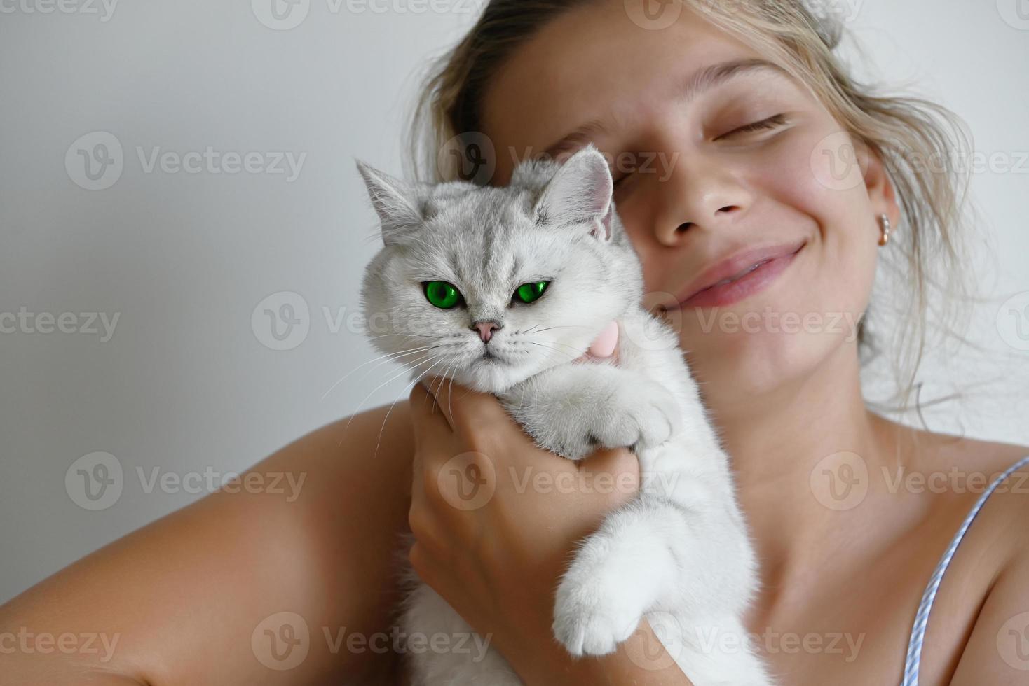 un gato blanco con flores verdes en manos de una hermosa niña sobre un fondo blanco. foto