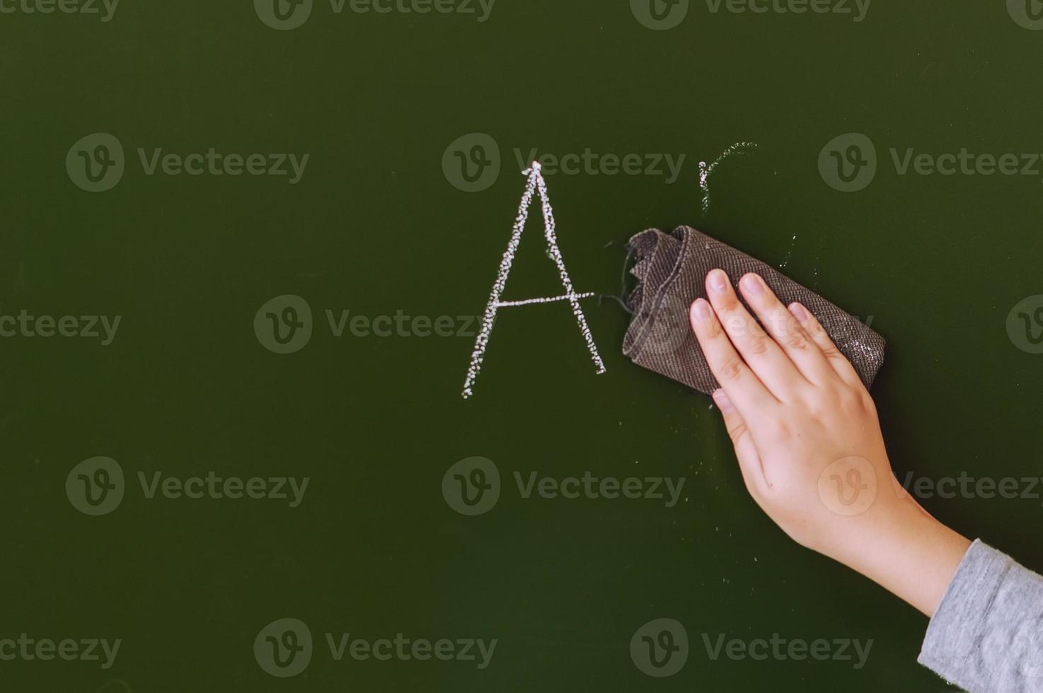 teenager's hand erases from a school board during a lesson at school photo