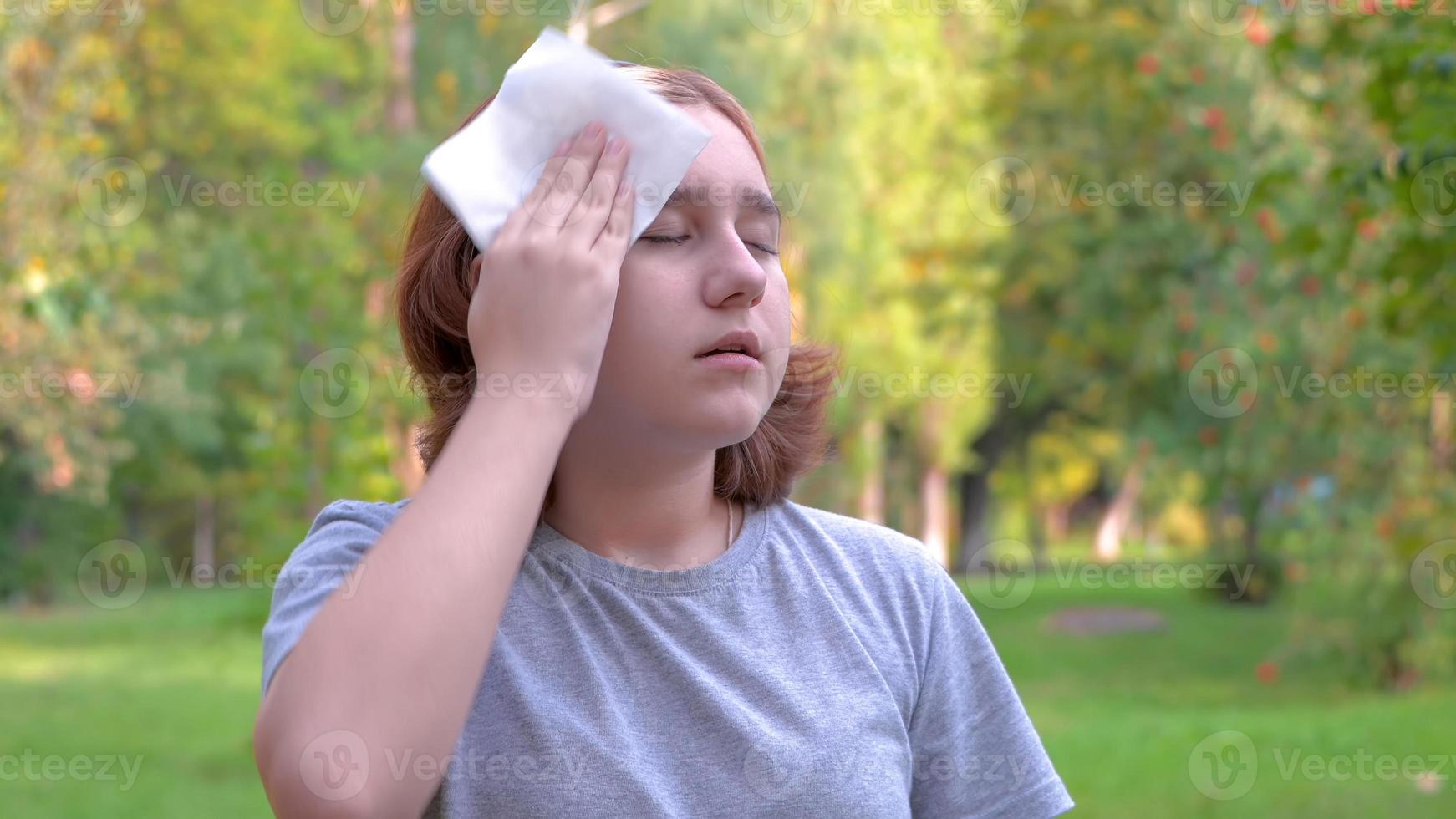 Girl wipes her face with a napkin from sweat in the heat, hygiene concept and etiquette , close-up photo