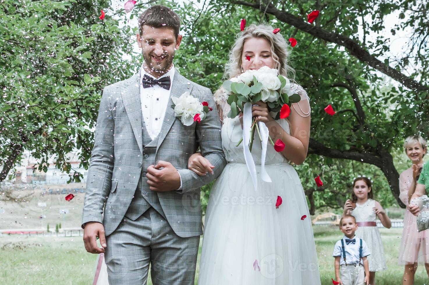 novios en la ceremonia de la boda. felicitaciones de los invitados. ducharse con pétalos de rosa. enfoque selectivo. grano de la película. foto