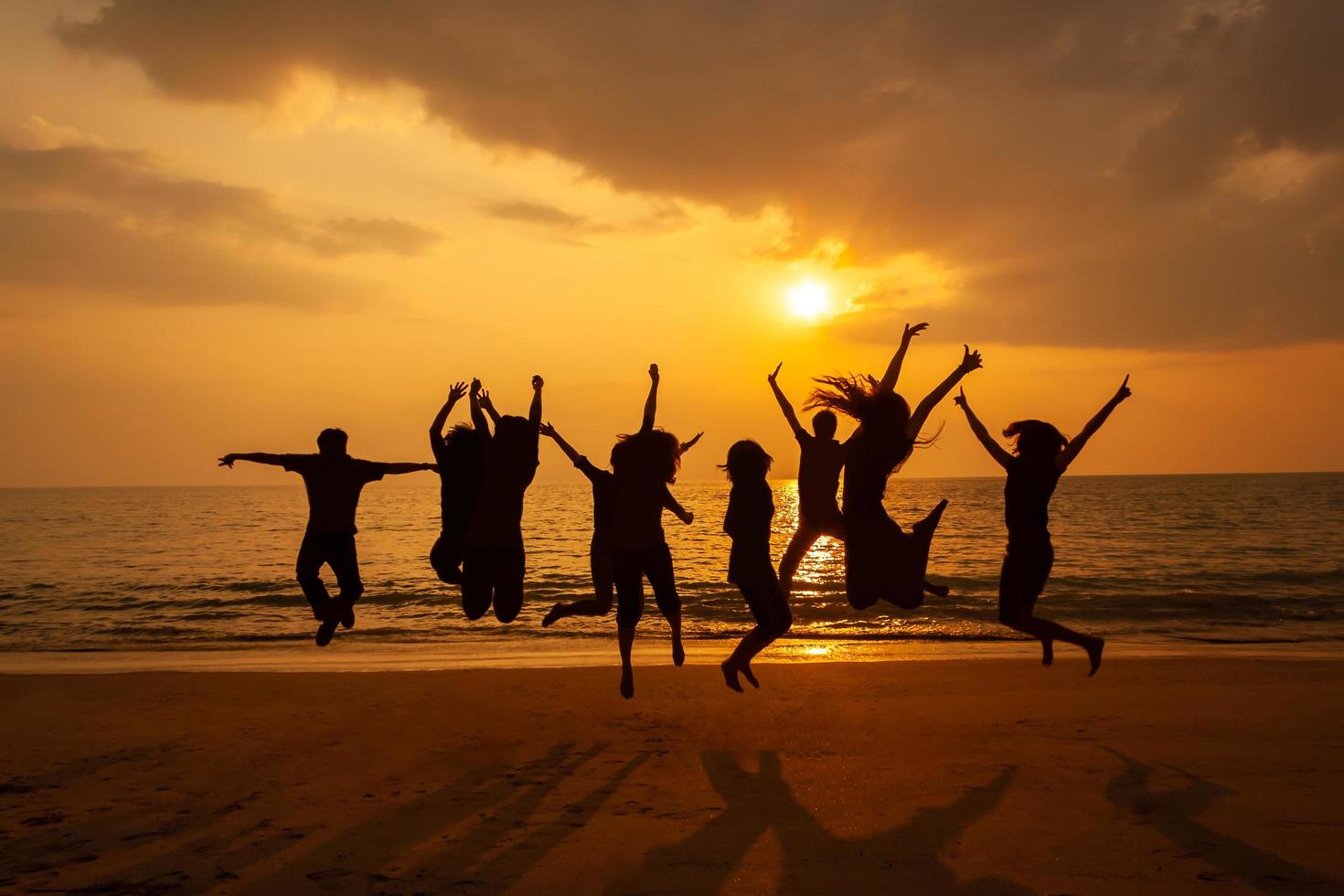 Foto de silueta de la celebración del equipo en la playa al atardecer