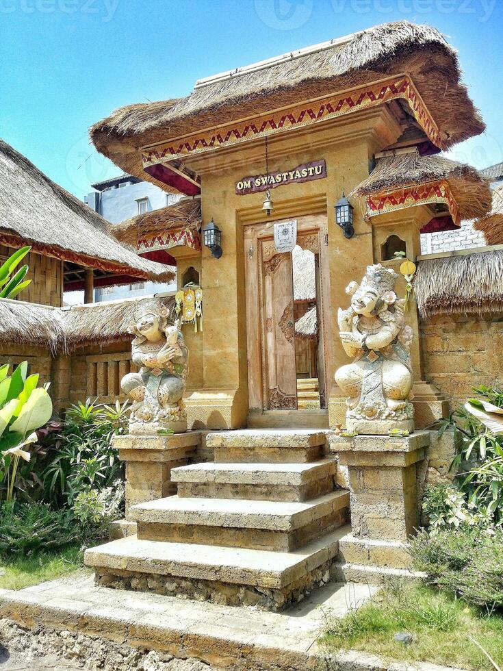 Balinese traditional building in the form of an entrance made of wood with a background of blue sky and green photo