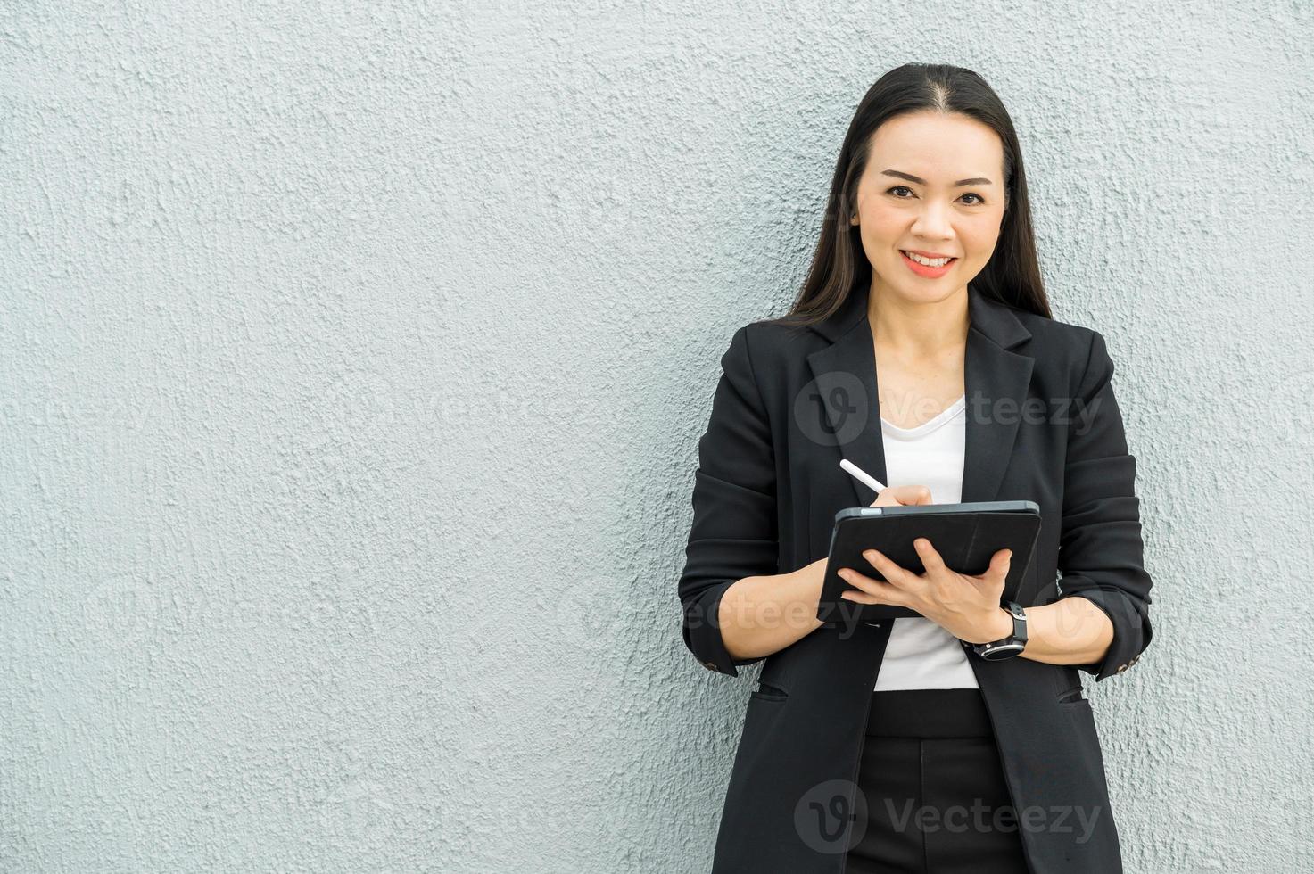 mujer trabajadora asiática sosteniendo la tableta en la oficina concepto de mujer trabajadora mujer de negocios con tecnología foto
