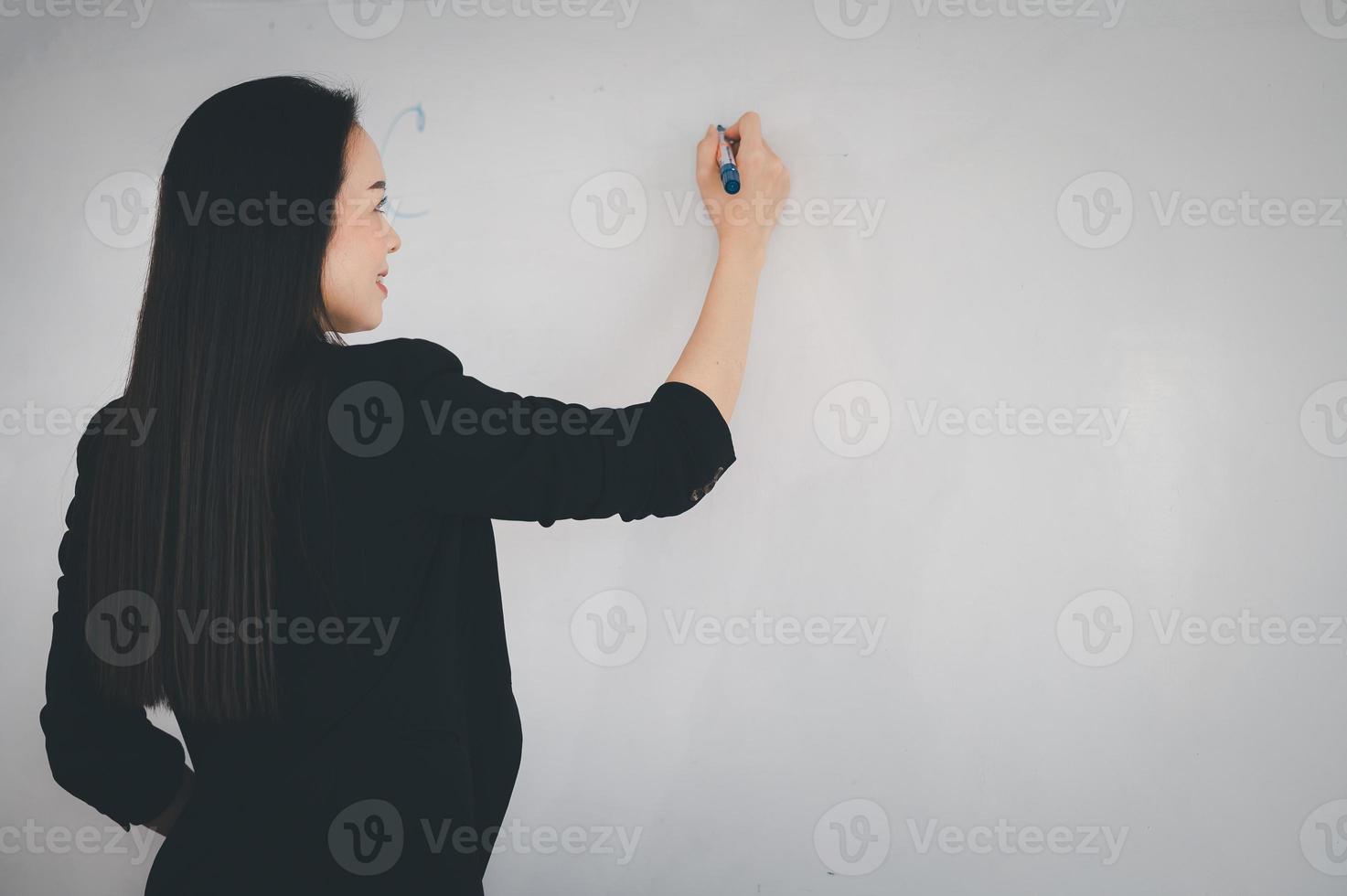 A young Asian teacher stands in front of a classroom at the university. photo