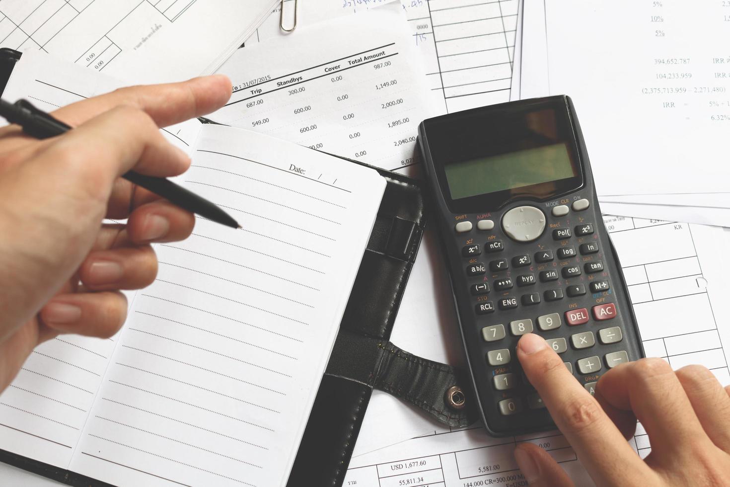 Business people counting on calculator sitting at the table. Close up of hands and stationery, soft focus photo