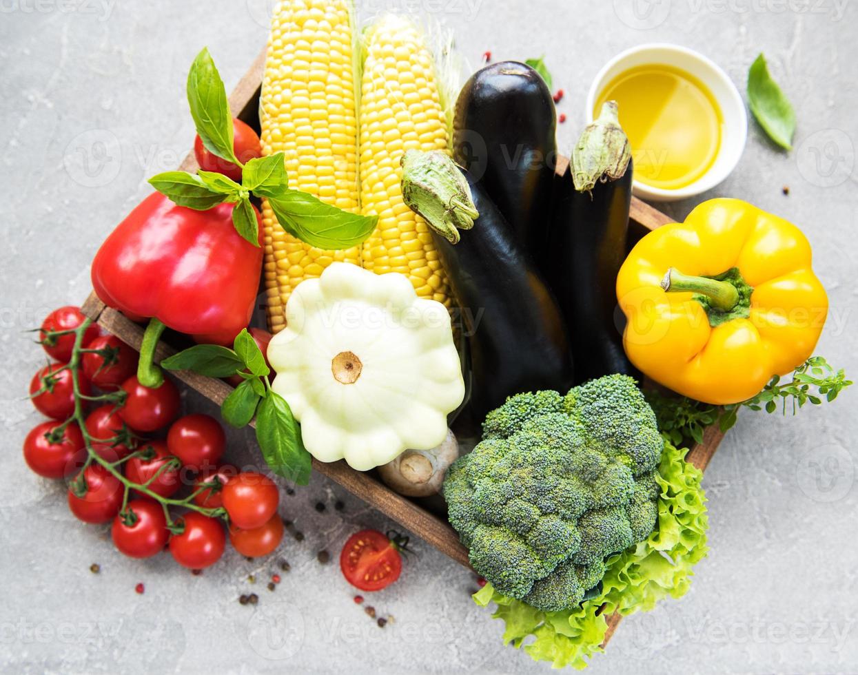 Diferentes verduras crudas y aceite de oliva. foto