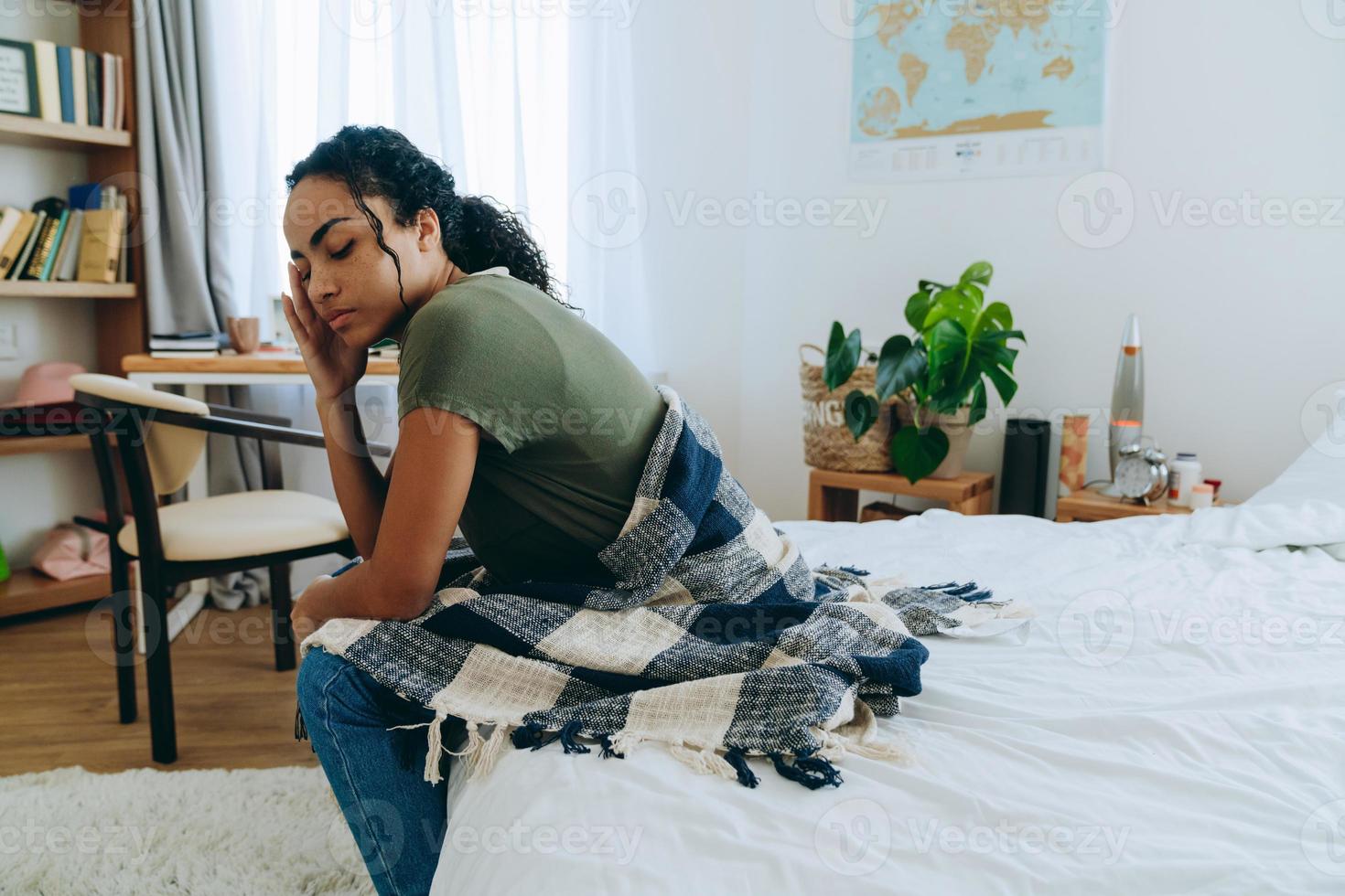 Upset African woman looks down while wrapped with a blanket photo