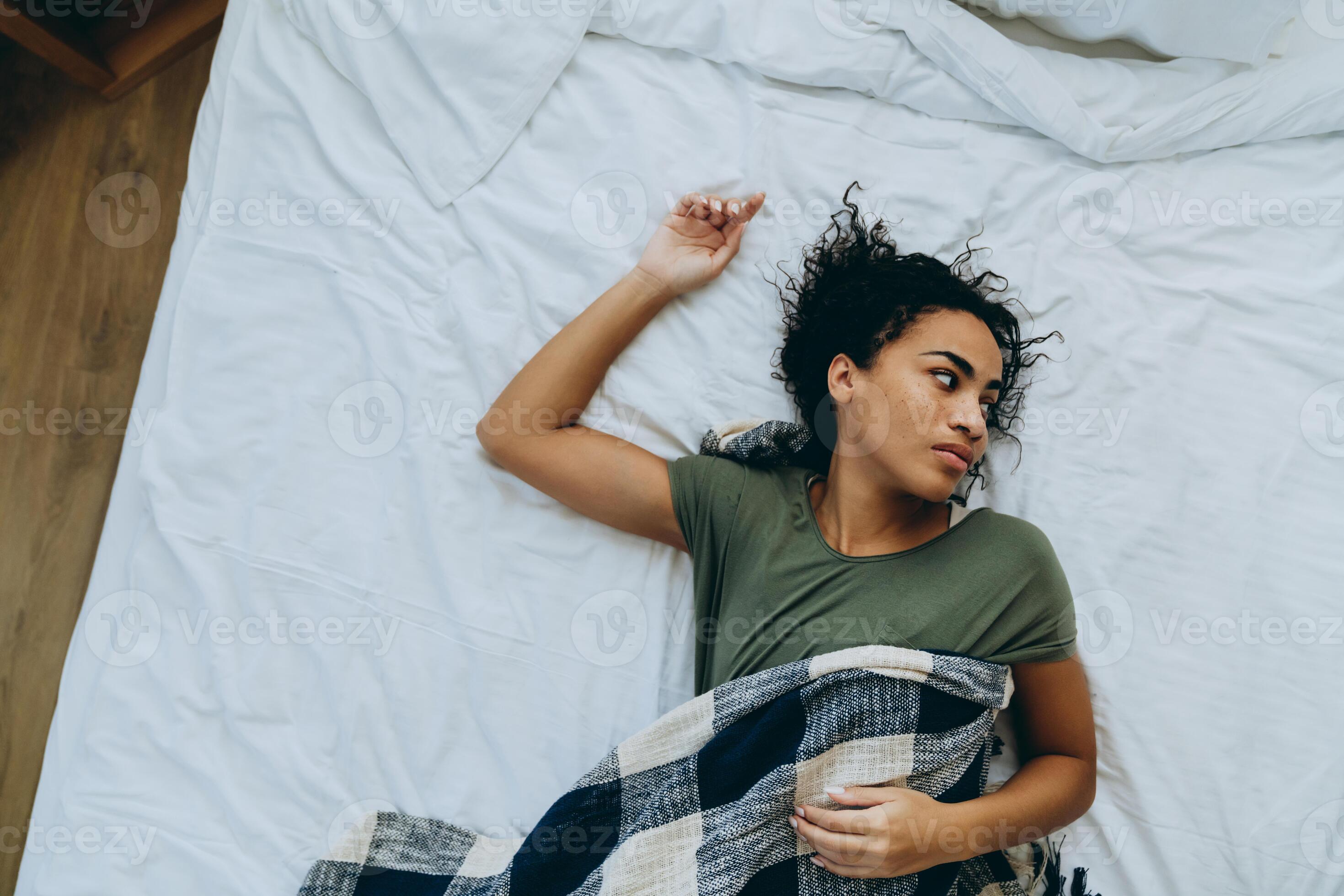 Overhead view of tired African woman wrapped herself in a blanket and