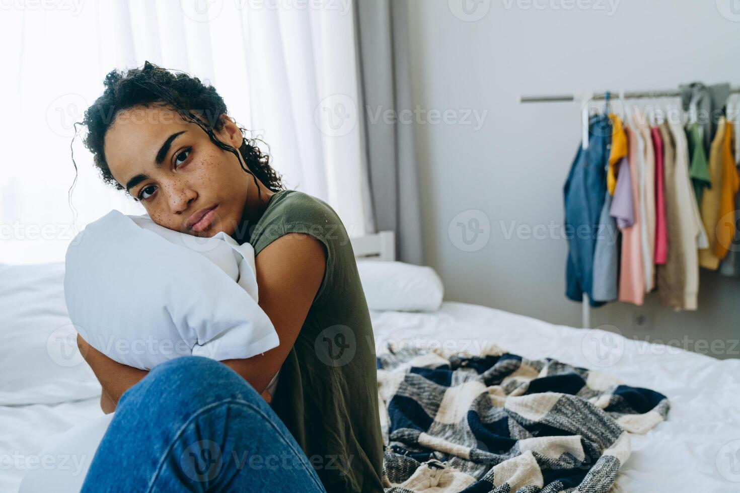 Sad African woman hugging pillow on the bed photo