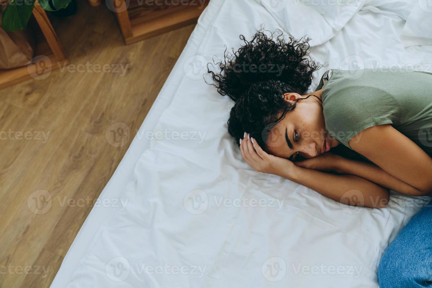 Overhead view of African sad woman lying on bed photo