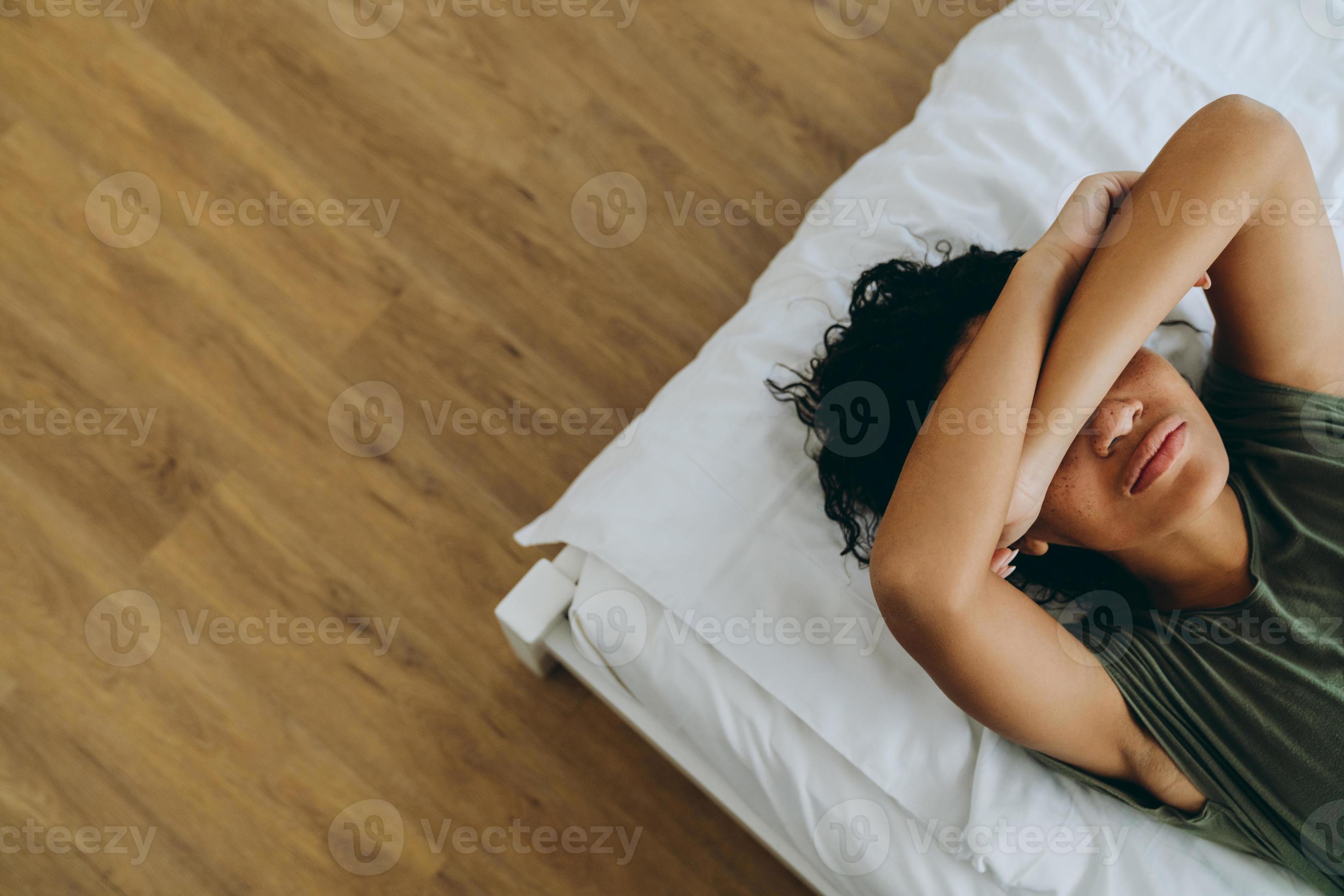 Overhead view of African woman covering her eyes on the bed photo
