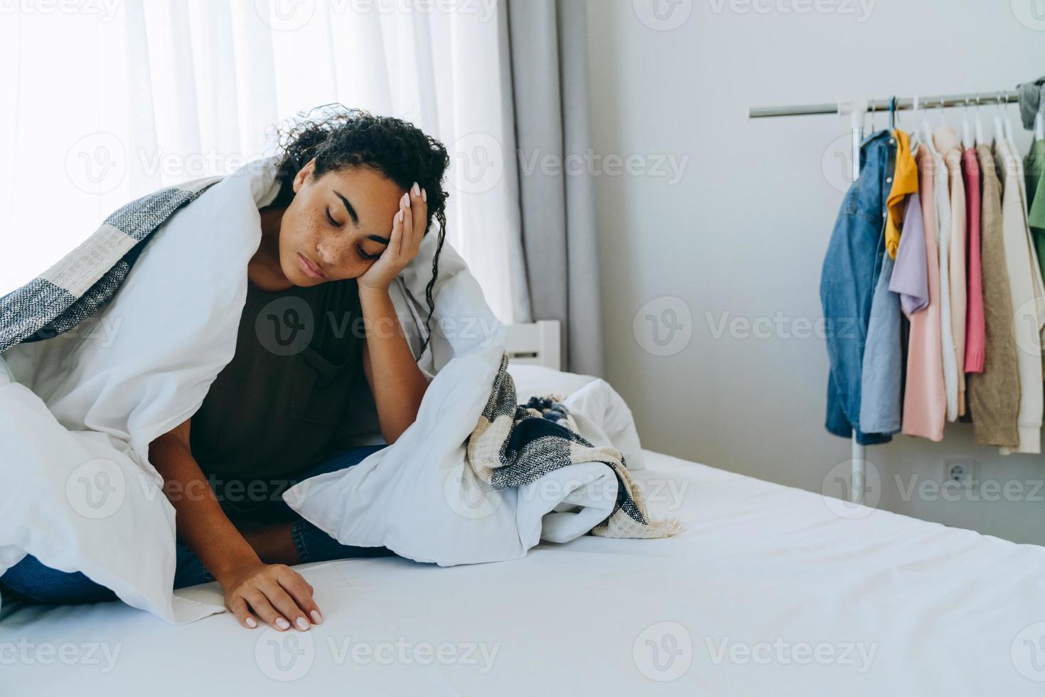 Sleepy African American woman with a blanket on the bed photo