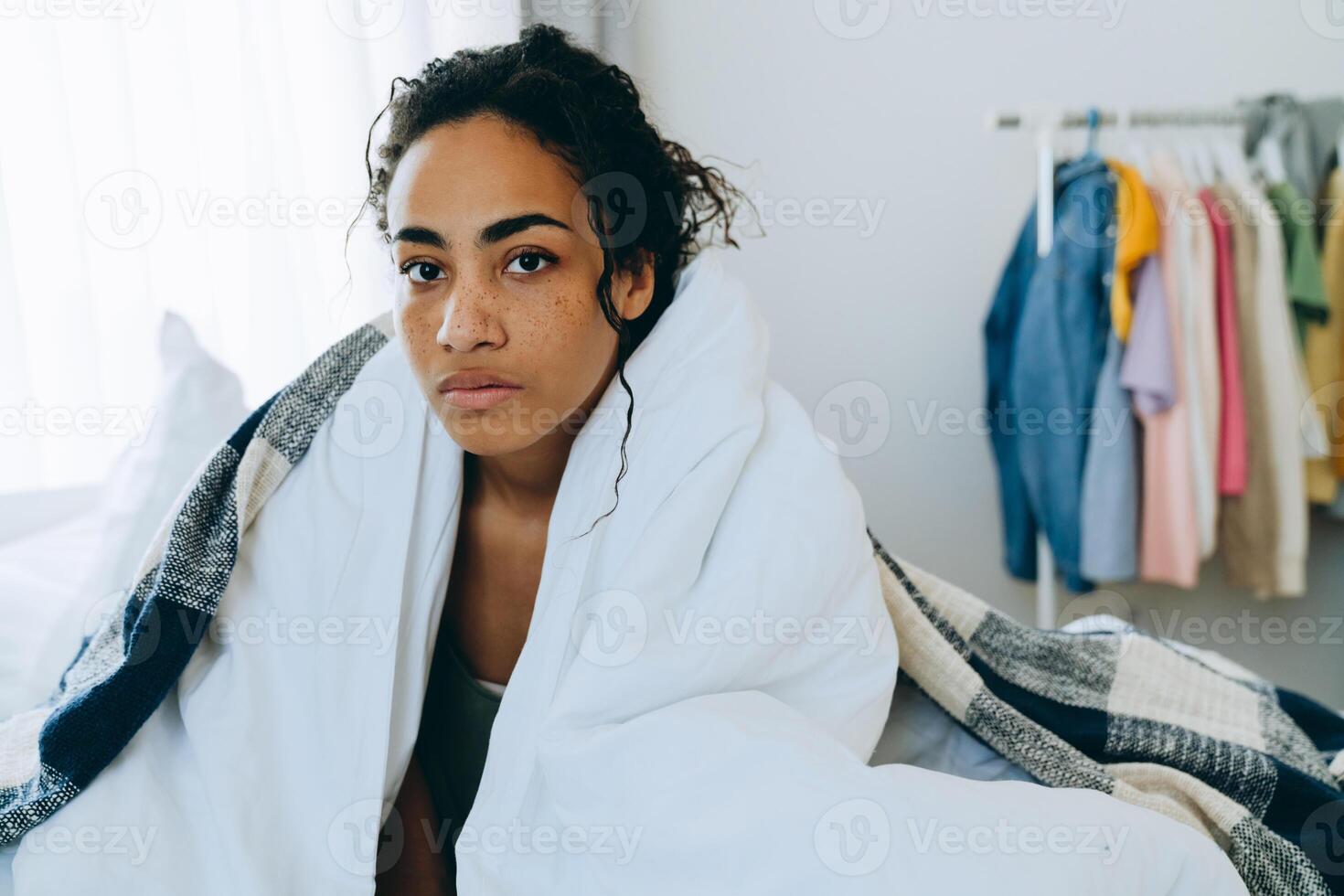 Pensive African American woman wrapped in a blanket looks at the camera photo