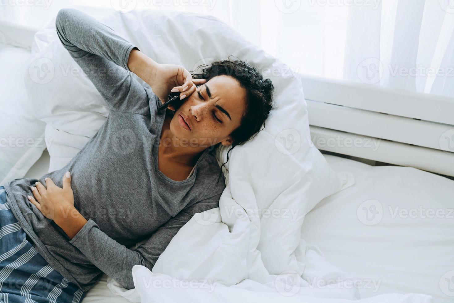 Young black woman talking on mobile phone while lying in bed photo