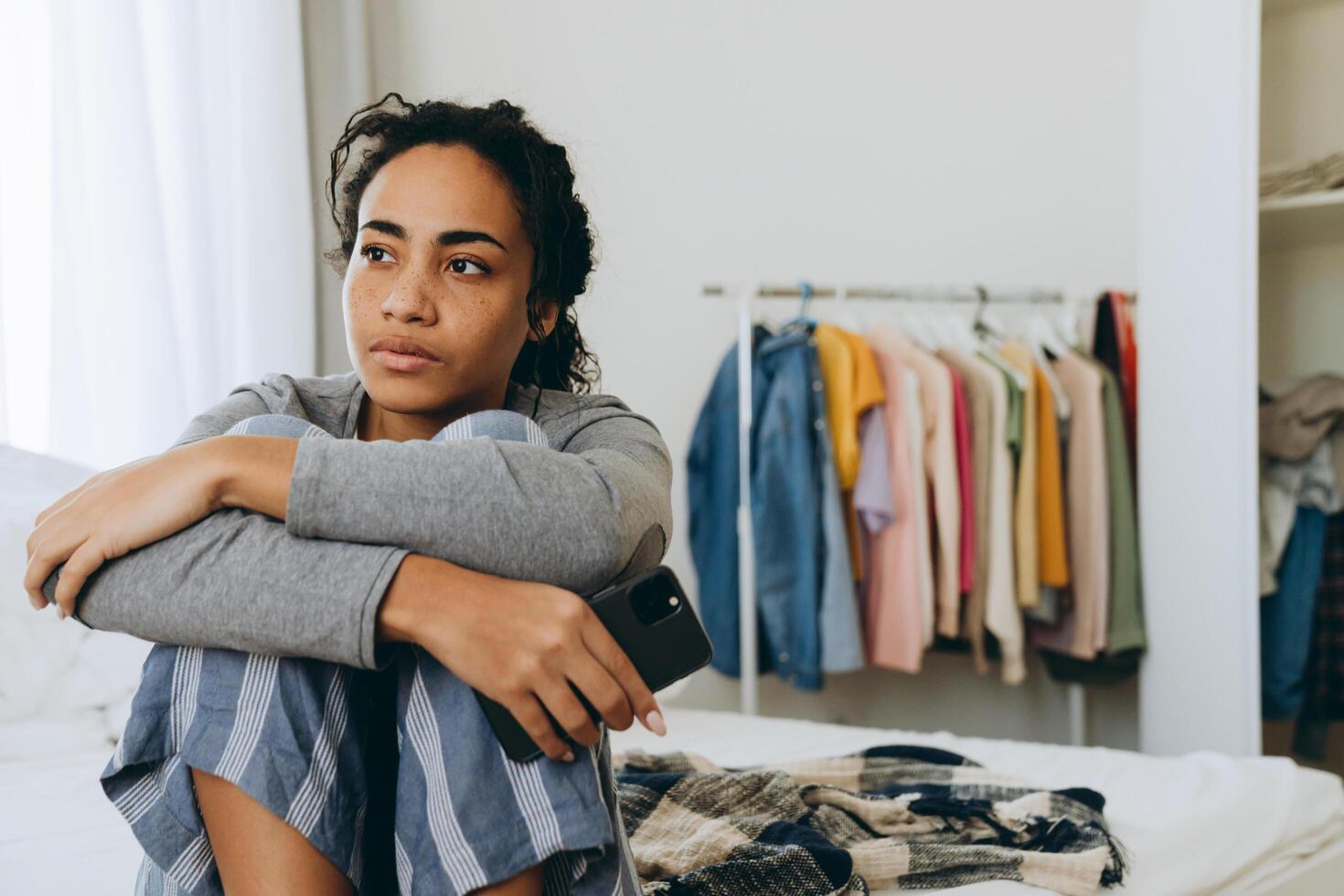 Young black woman sitting on bed using mobile phone  photo