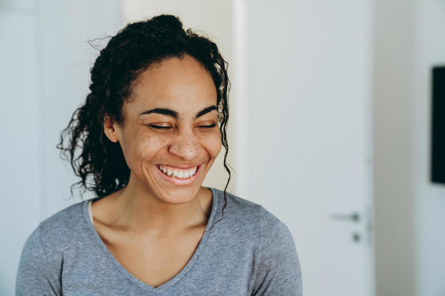 Black woman laughing with eyes closed during spending time at home photo