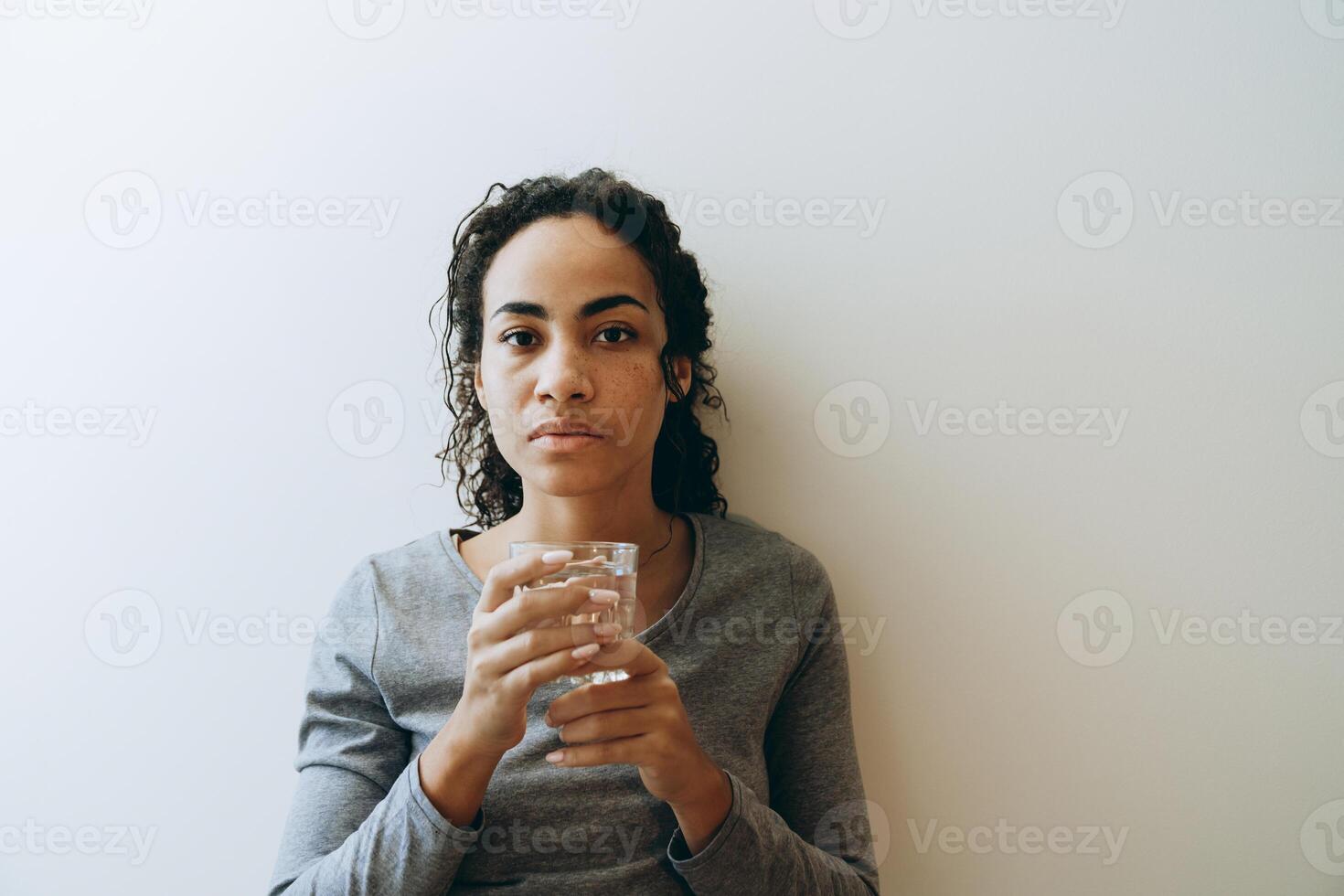 Joven mujer negra bebiendo agua durante pasar tiempo en casa foto