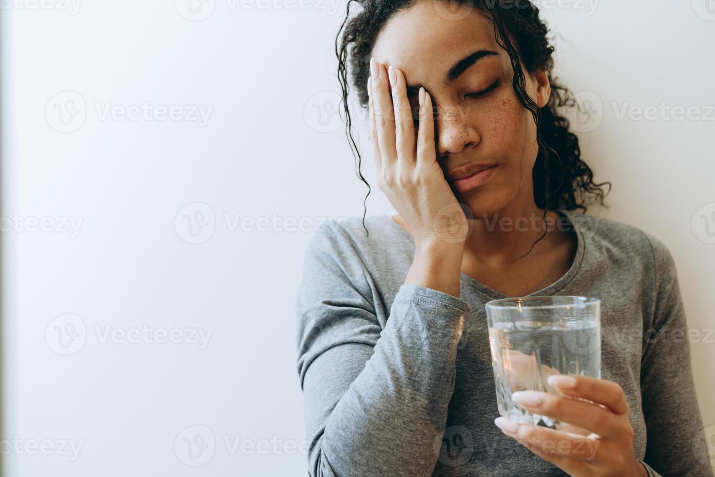 Joven mujer negra bebiendo agua durante pasar tiempo en casa foto