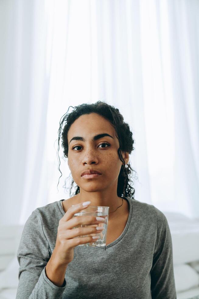 Joven mujer negra bebiendo agua durante el tiempo en casa foto