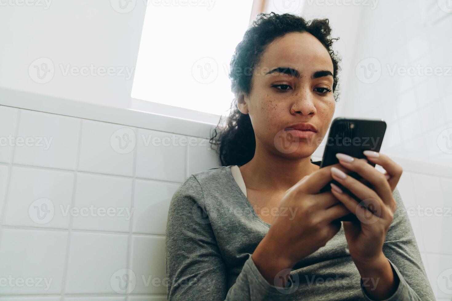mujer negra, utilizar, teléfono móvil, mientras, posición, en, baño