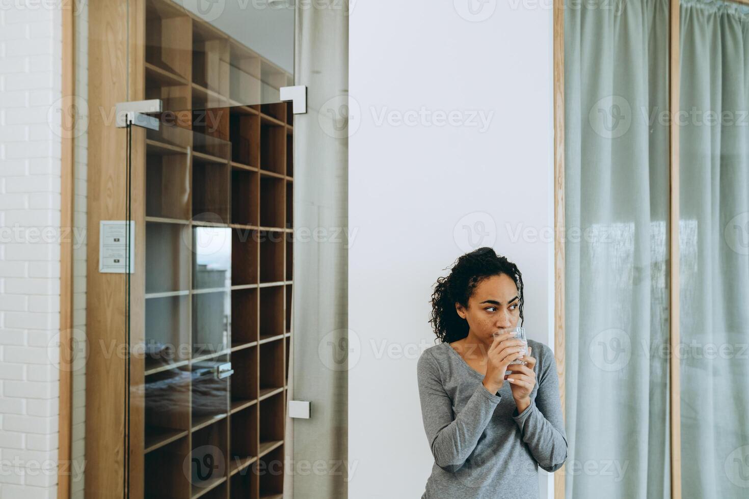 Joven mujer negra bebiendo agua durante pasar tiempo en casa foto