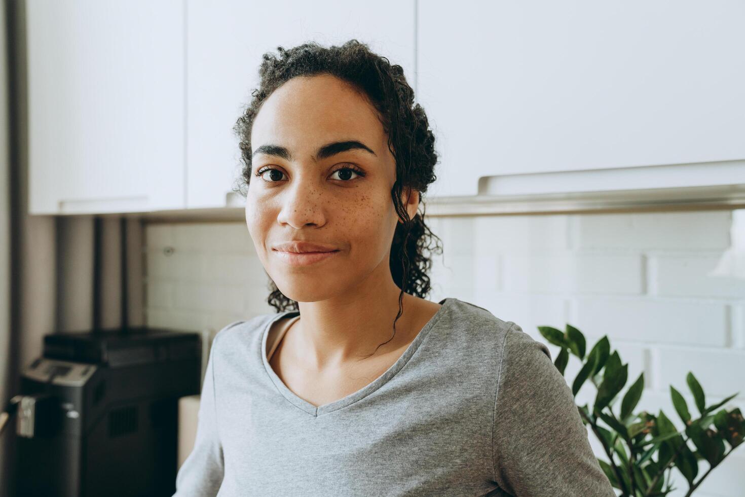 Young black woman smiling and looking at camera in her kitchen photo