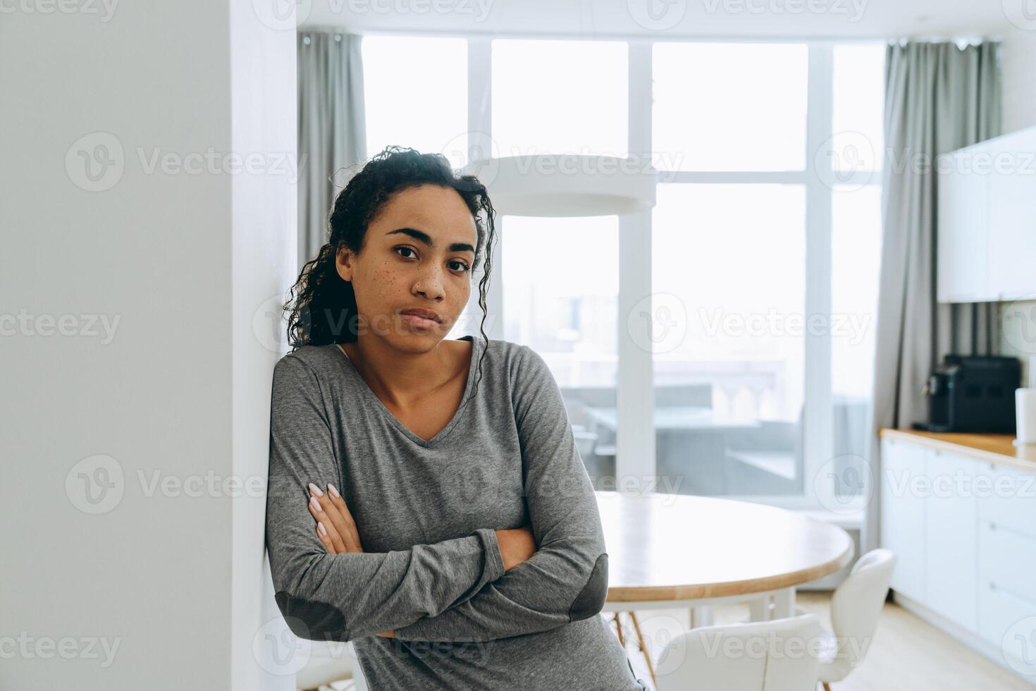 Mujer negra mirando a la cámara mientras está apoyado en la pared en casa foto