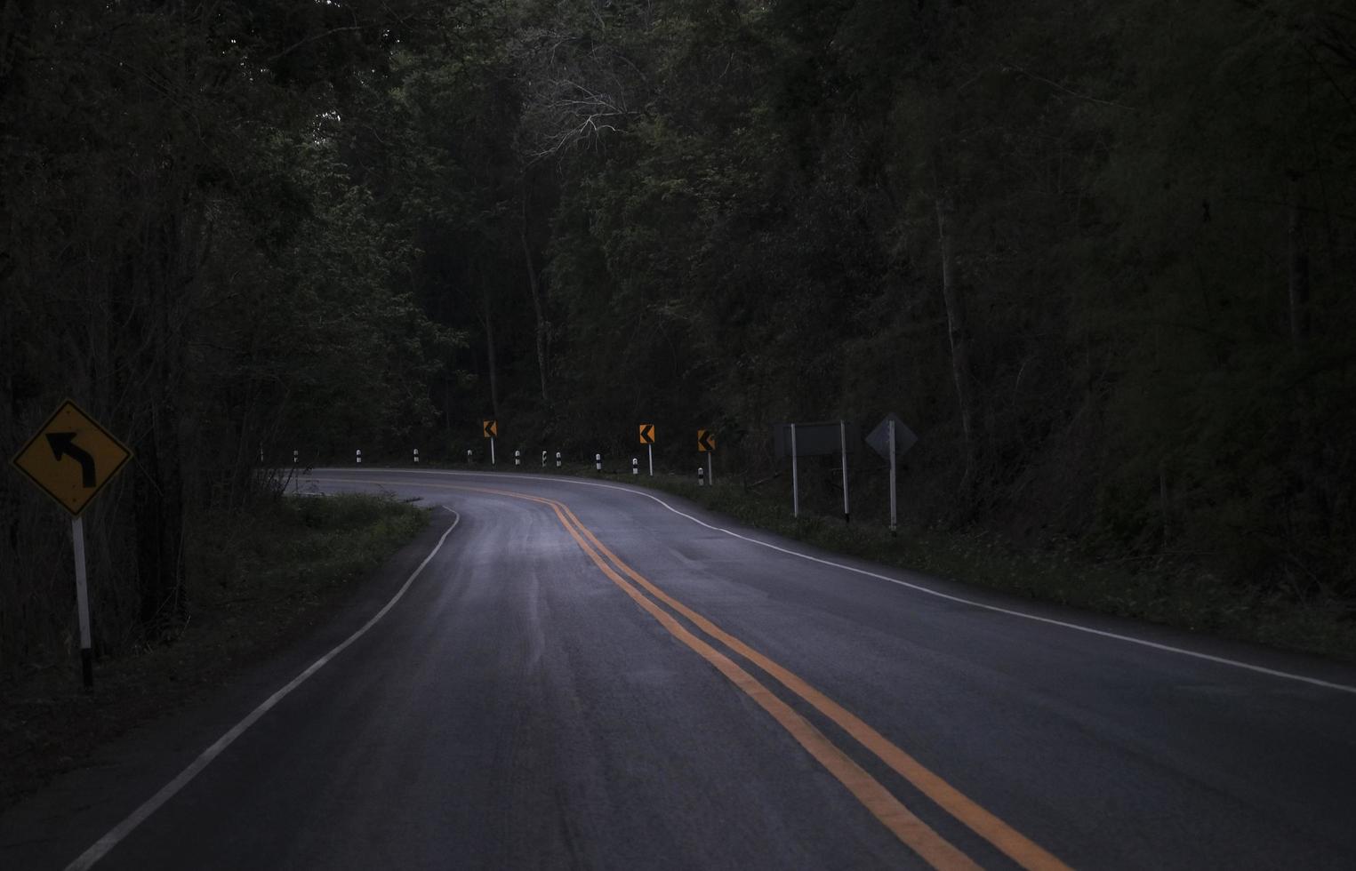 Road on the dark view on the mountain road among green forest trees - curve asphalt road lonely scary at night photo