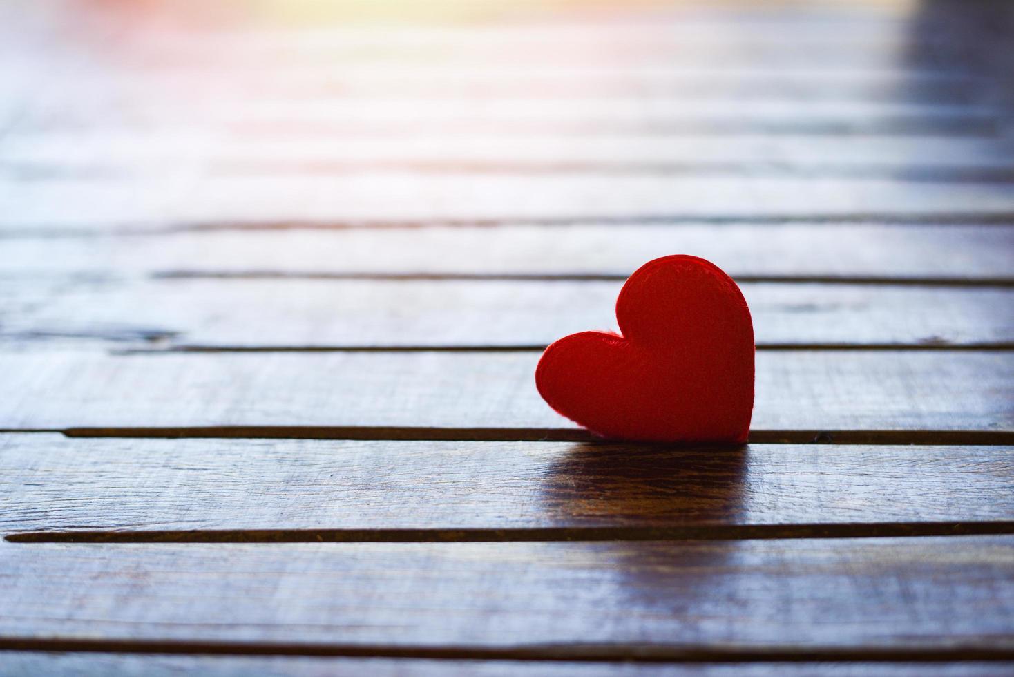 Tarjeta de vacaciones día de San Valentín corazón rojo sobre madera vieja con puesta de sol para el concepto de filantropía - corazones sobre un fondo de madera donar ayudar a dar amor cuidar foto