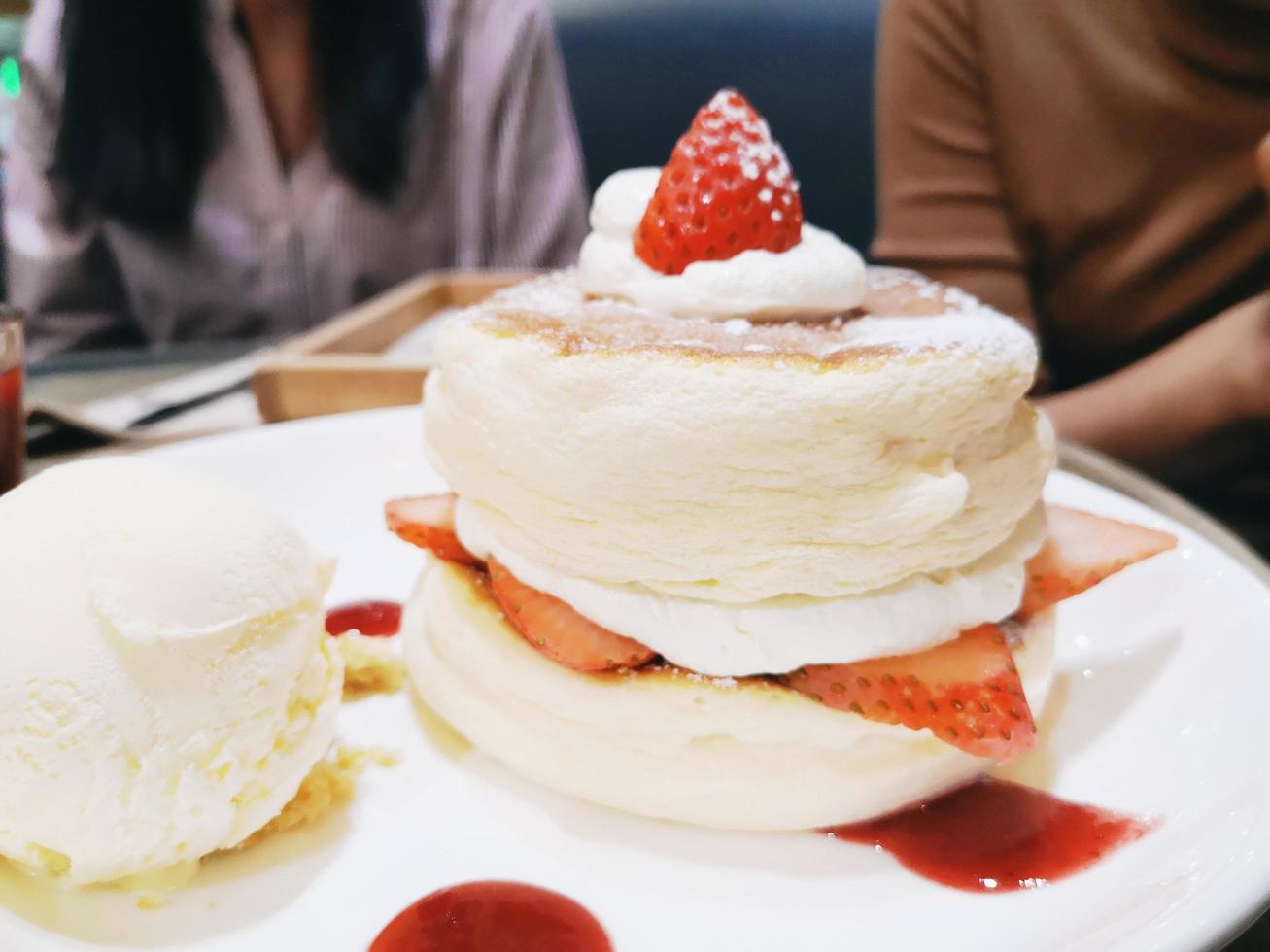 Panqueques esponjosos caseros y almíbar dulce: deliciosos panqueques con salsa de fresa y helado en la mesa del comedor en la cafetería restaurante foto