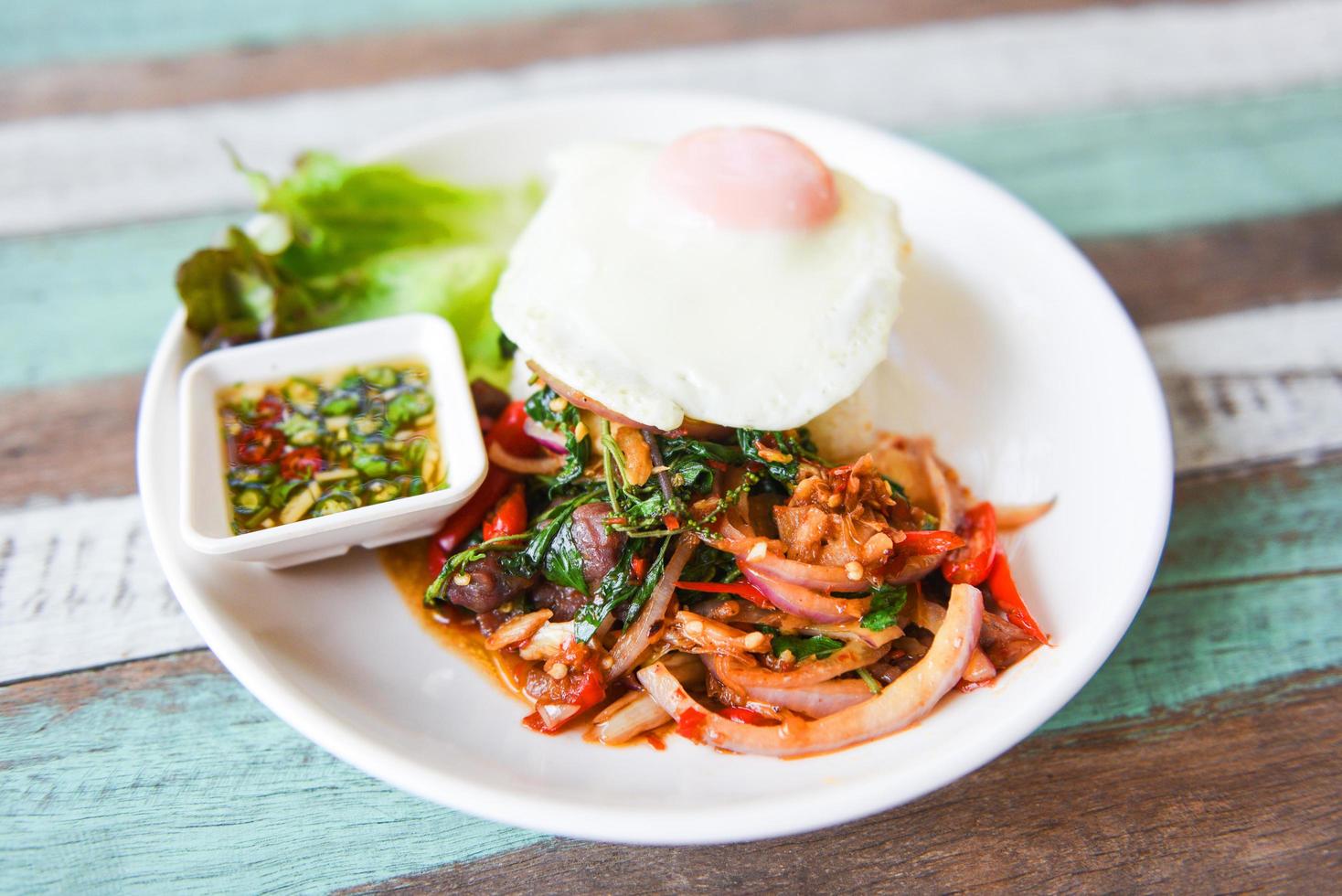 Rice topped with stir fried pork beef meat with holy basil and fried egg - Thai food spicy fried recipe with vegetables and chili sauce photo