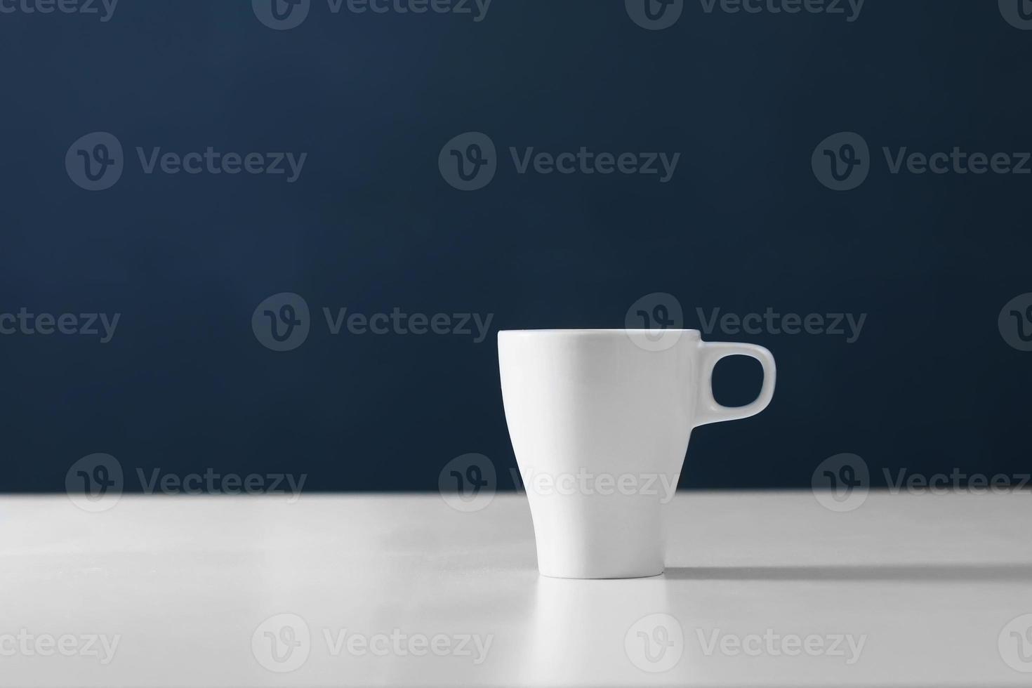 White cup on blue background. Blank ceramic cup photo