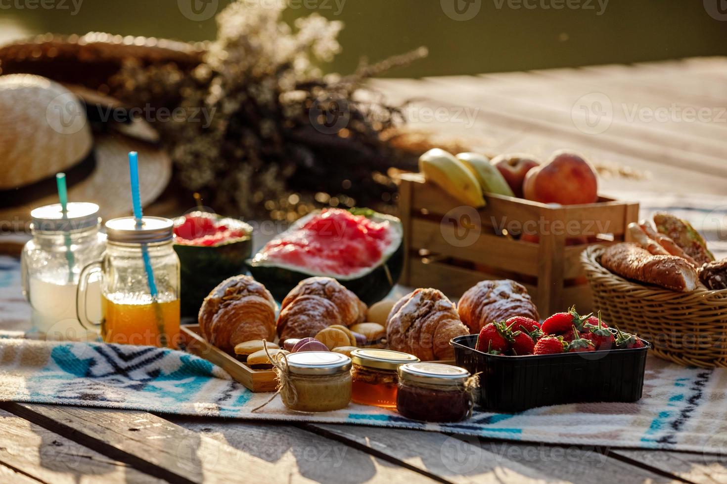 Picnic at the park. Fresh fruits, ice cold sparkling drinks and croissants on a hot summer day. Picnic lunch. selective focus photo