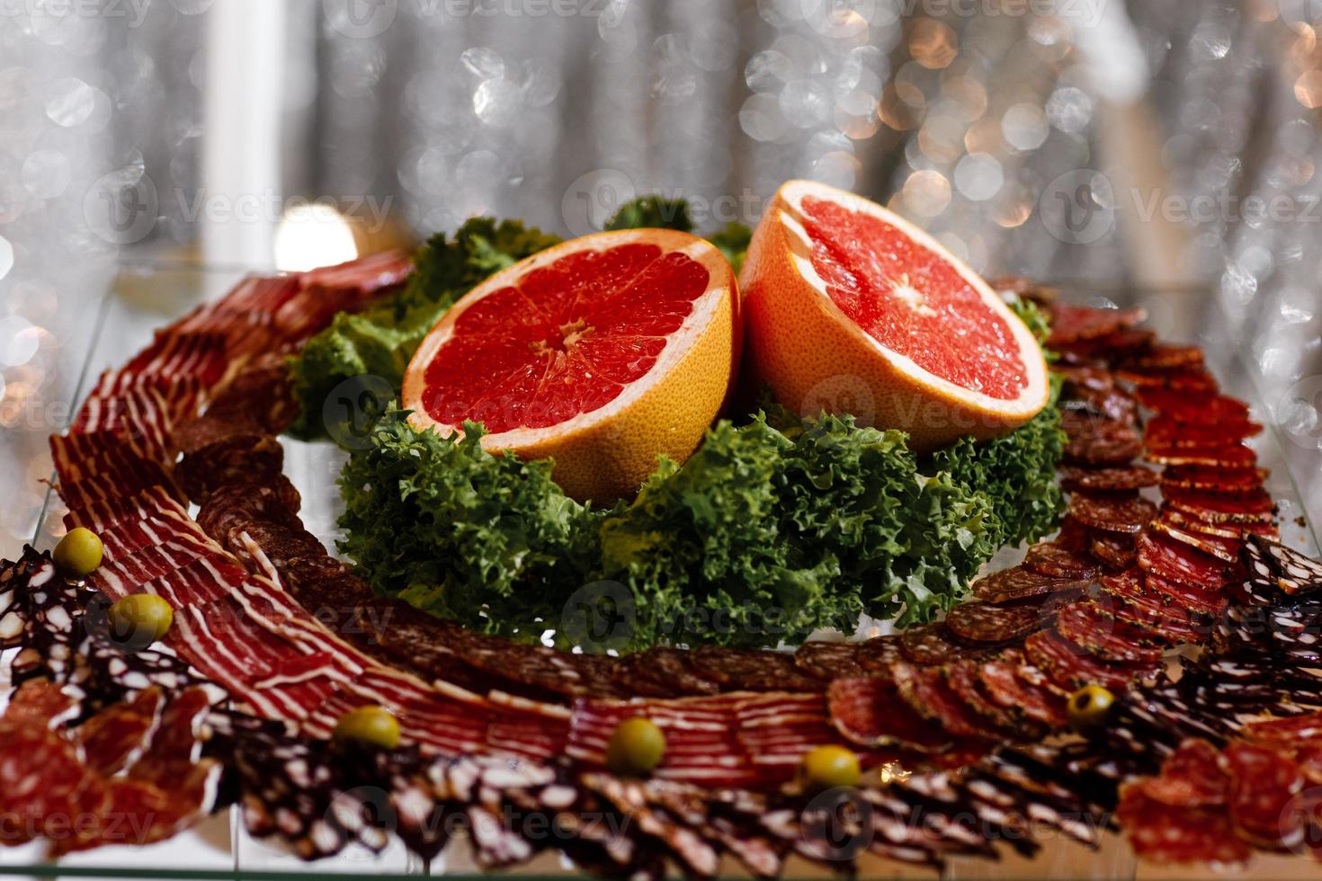 meat appetizer. Fresh sliced fruits on celebratory table. slicing sausage and grapefruit photo