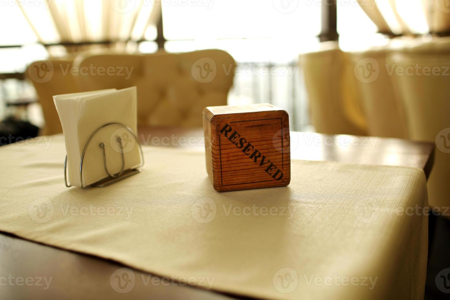 Reserved sign on the table. A wooden plaque has a word reserved placed on the dining table in a restaurant, shot with blurred background. the reservation sign written Reserved put on wood table photo