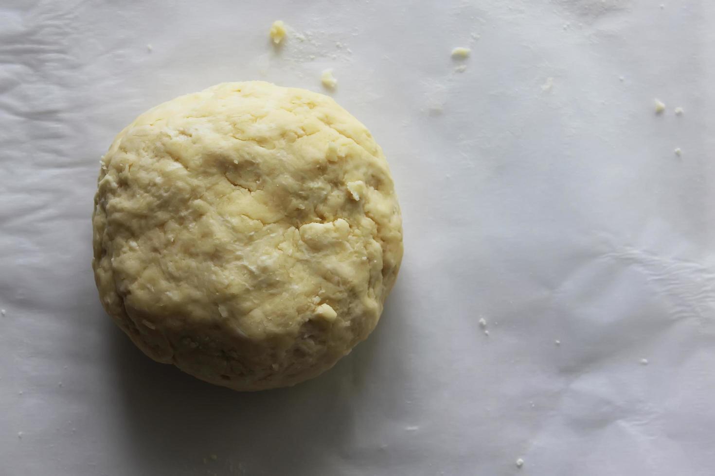 A ball of dough lies on a white tablecloth on the table. Homemade cake. Housework. photo