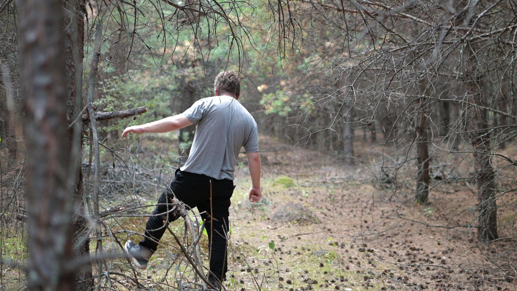 a lonely man with glasses walks through a dark autumn forest waddling from one foot to the other photo