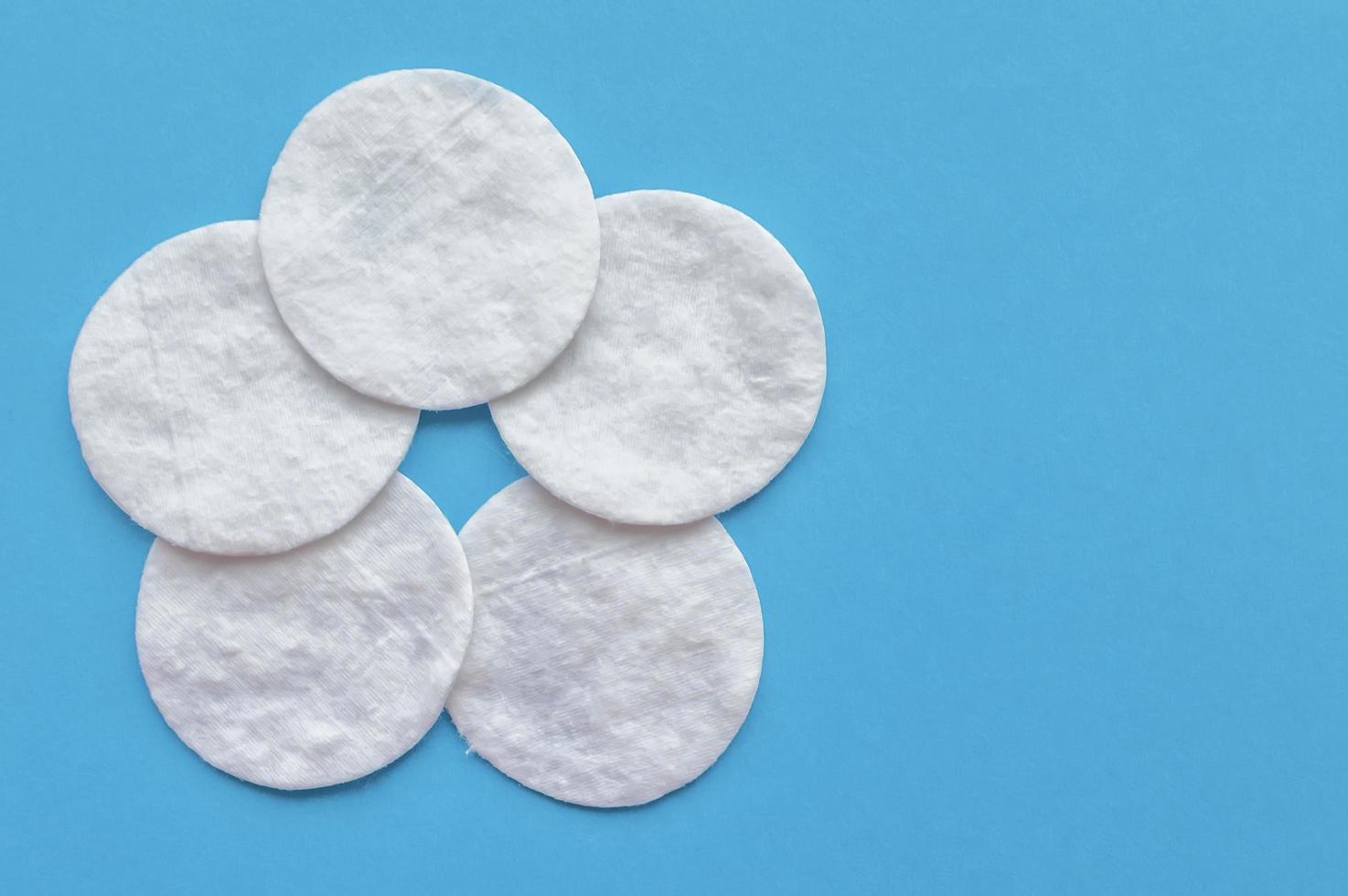 Cotton pads in the form of a flower on a blue background with a place for writing. The concept of body care. photo