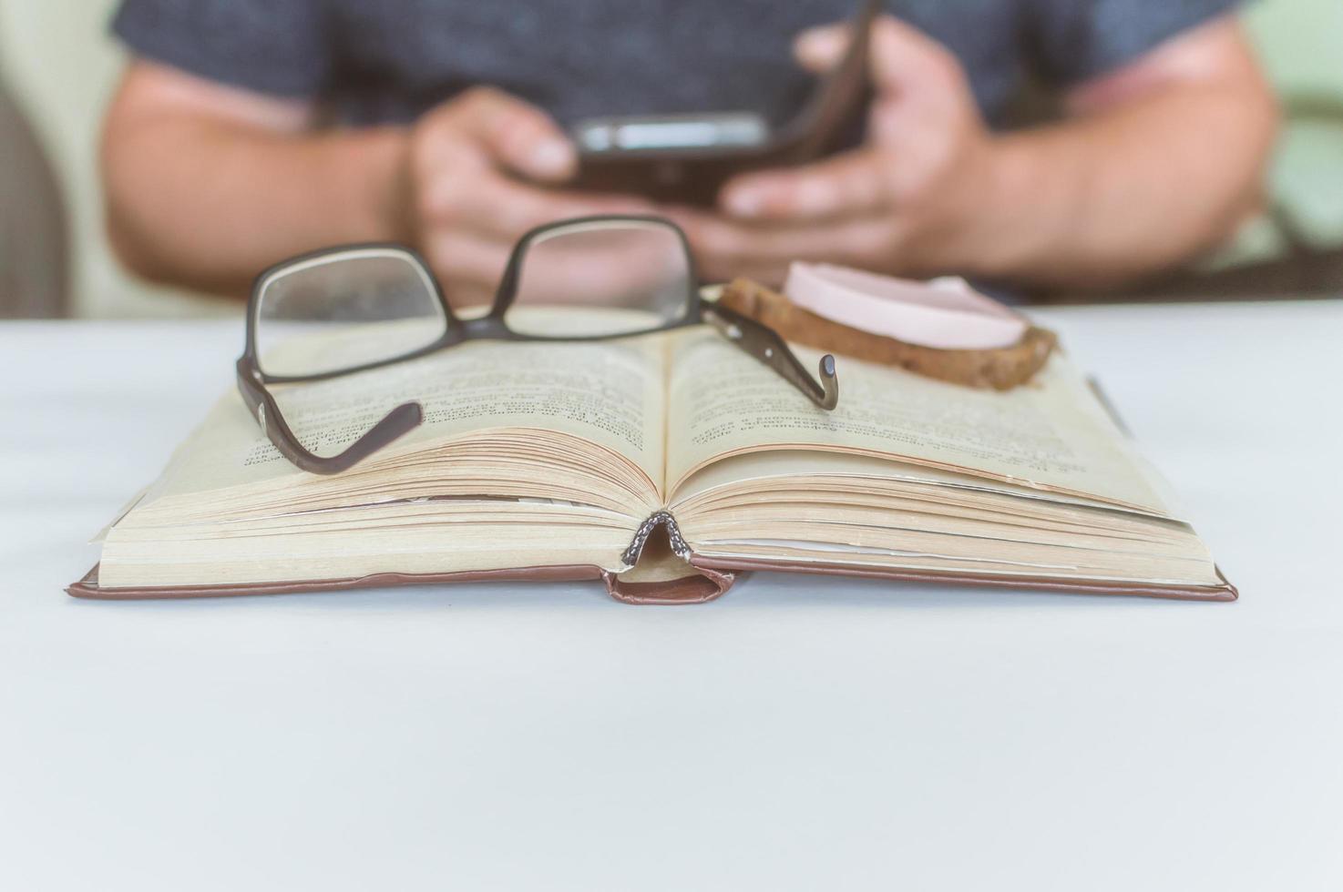 man reading a book at the table, having a snack while reading, a short break photo