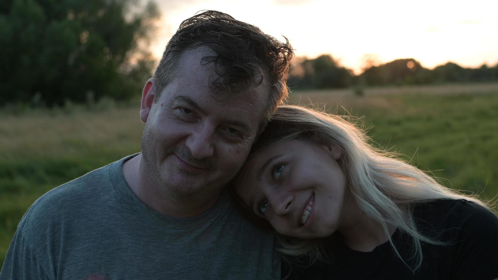 Papá e hija adulta se abrazan en el contexto de la naturaleza otoñal al atardecer foto