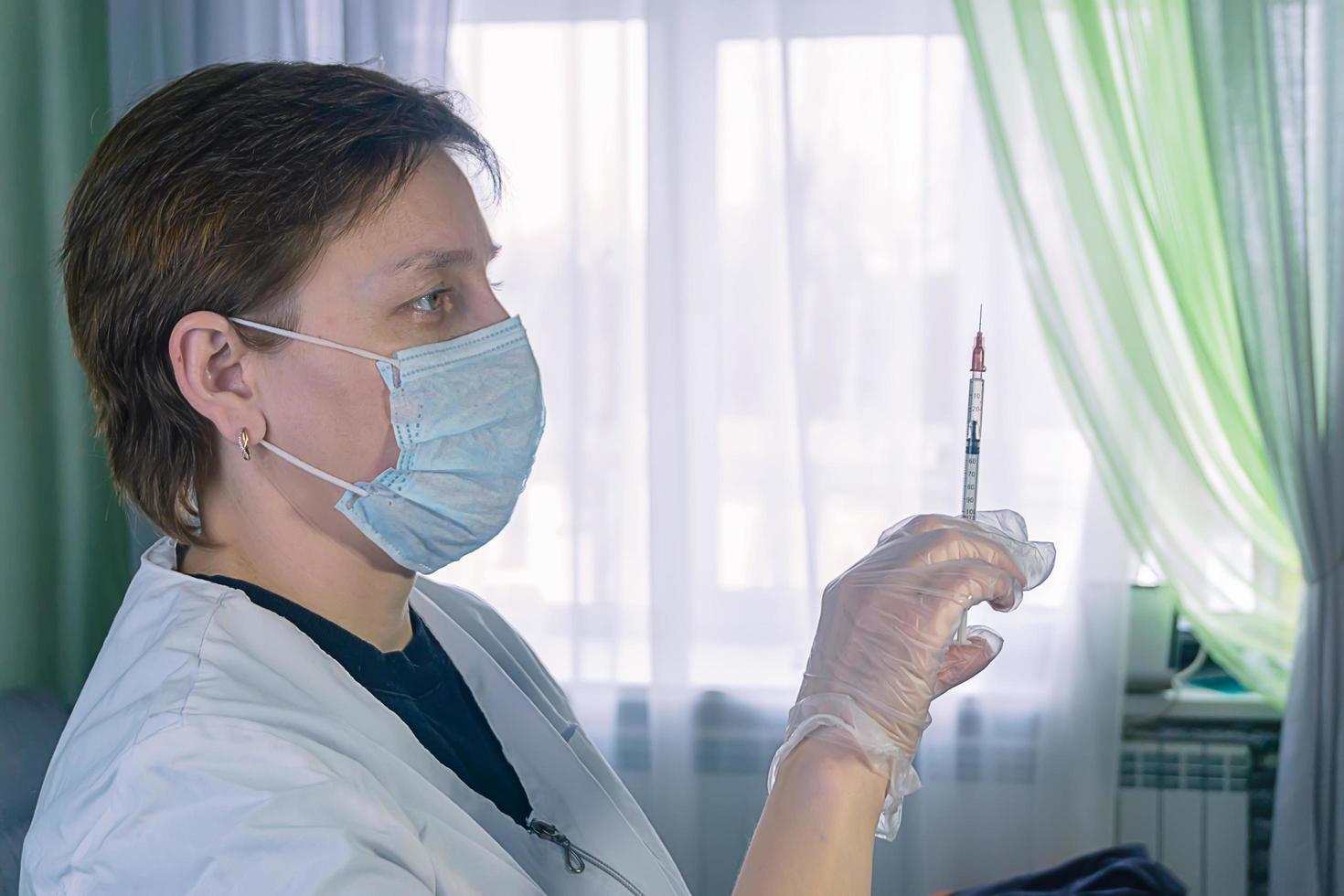 a woman in a white coat with a syringe in hand photo