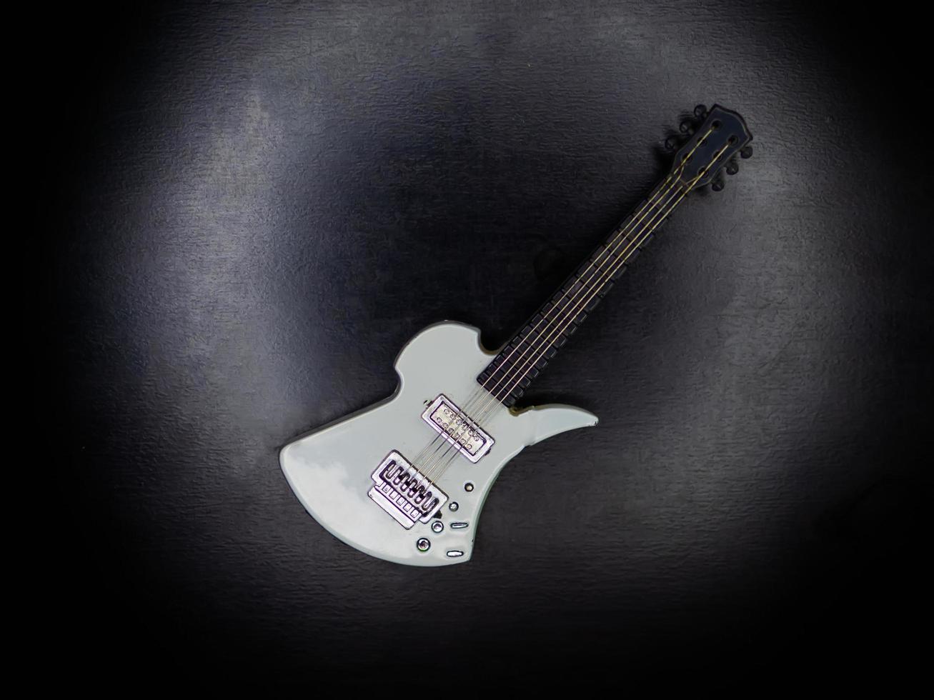 a small white guitar keychain on a black background kind of super photo