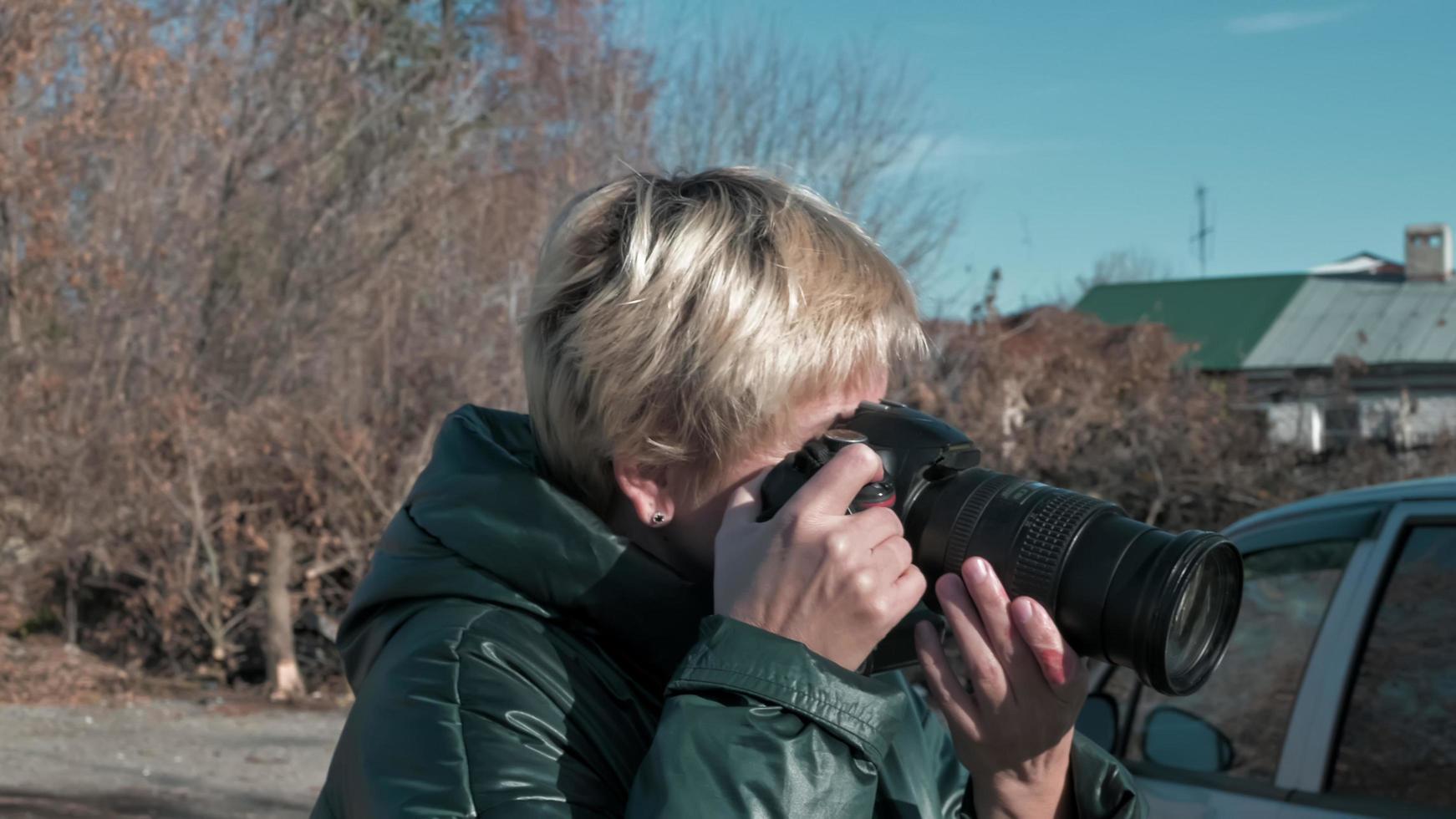 the girl is a forensic photographer in a dark jacket. a traveler takes pictures of an old village with a camera photo