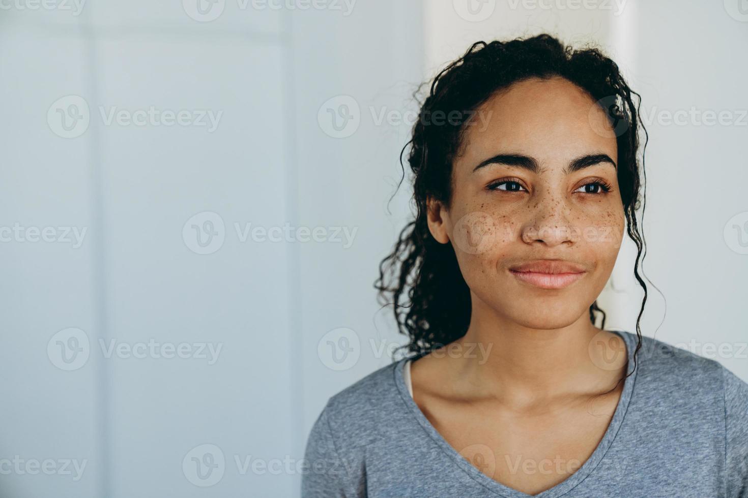 Mujer negra sonriendo y mirando a un lado durante pasar tiempo en casa foto