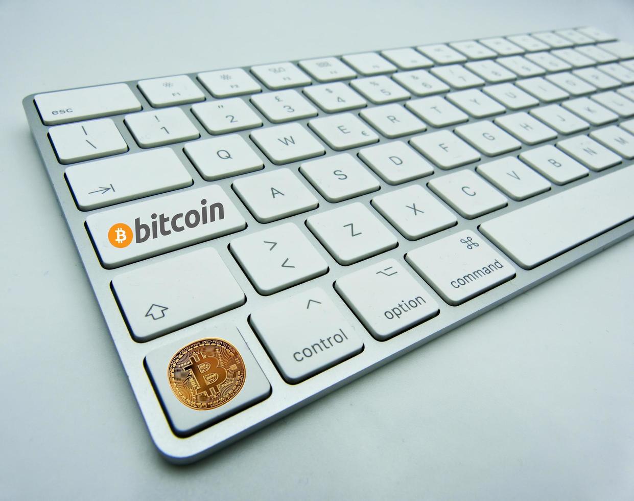 Golden Bitcoin symbol on a button of a white computer keyboard. New technological economy concept. photo