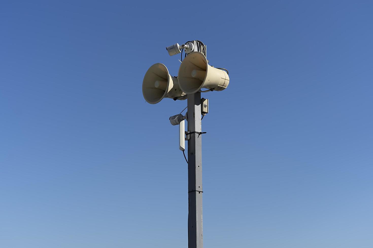 A pole with a loudspeaker on a blue sky background photo